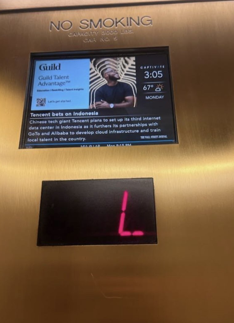 Guild ad running on a screen inside an office elevator.