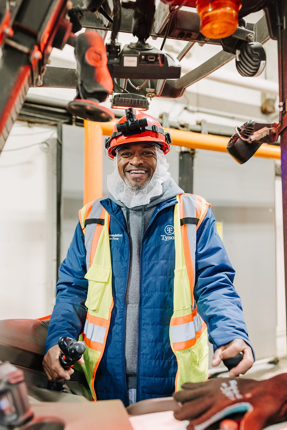 A worker in a hard hat and high-visibility jacket photographed at a forklift.